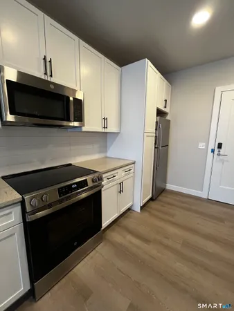 a kitchen with stainless steel appliances white cabinets and a stove top oven