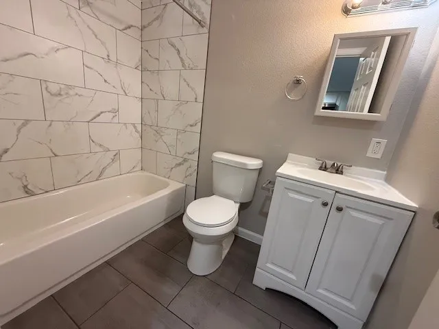 a white toilet sitting next to a bathroom sink and vanity