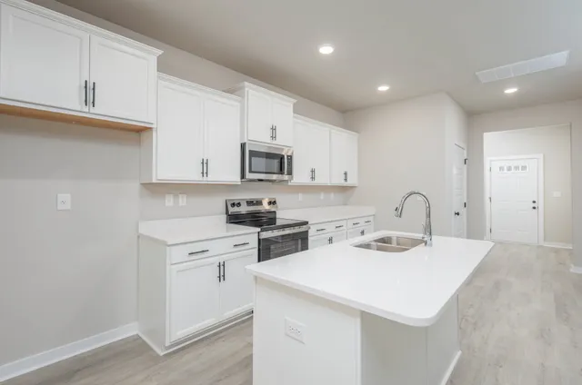 a kitchen with kitchen island a sink appliances cabinets and a counter top space