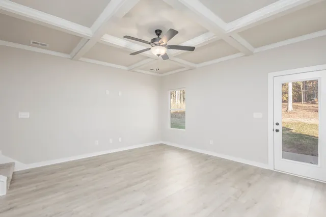 an empty room with wooden floor fan and windows