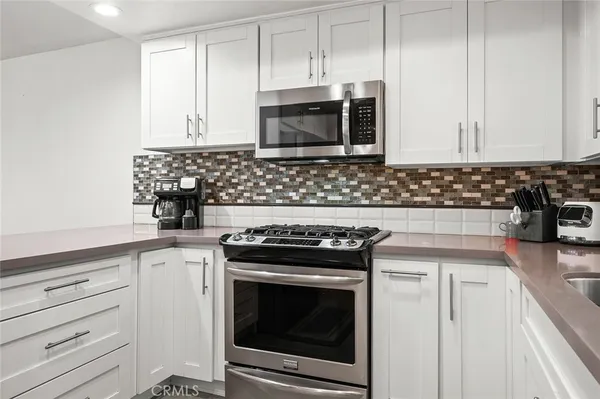 a kitchen with granite countertop white cabinets and stainless steel appliances