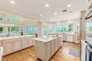 a large white kitchen with kitchen island a sink white cabinets and stainless steel appliances