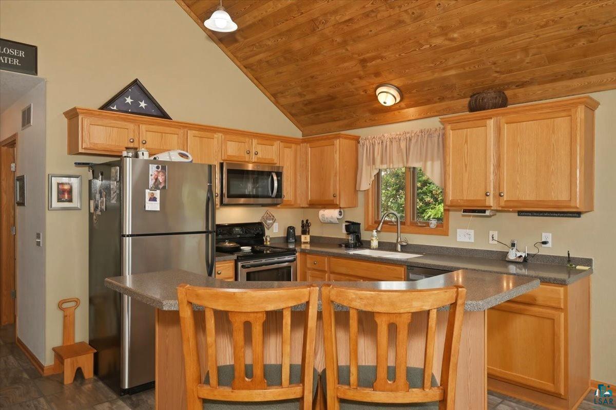 8162 South Dowling Road West Superior, WI 54880 - Photo 5 of 15 Kitchen featuring wood-finish vaulted ceilings, light-tone cabinetry, stainless steel appliances, a breakfast bar, and wood-finish flooring