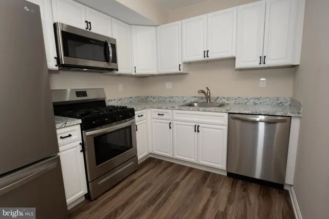 a kitchen with stainless steel appliances granite countertop a stove a microwave and a hard wood floors