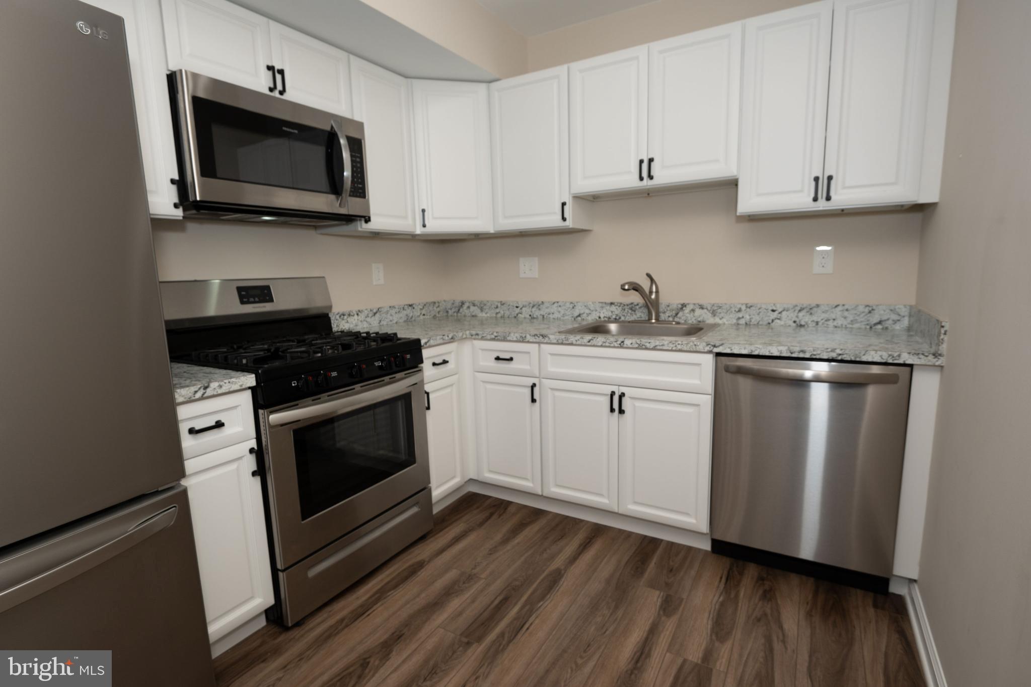 a kitchen with stainless steel appliances granite countertop a stove a microwave and a hard wood floors