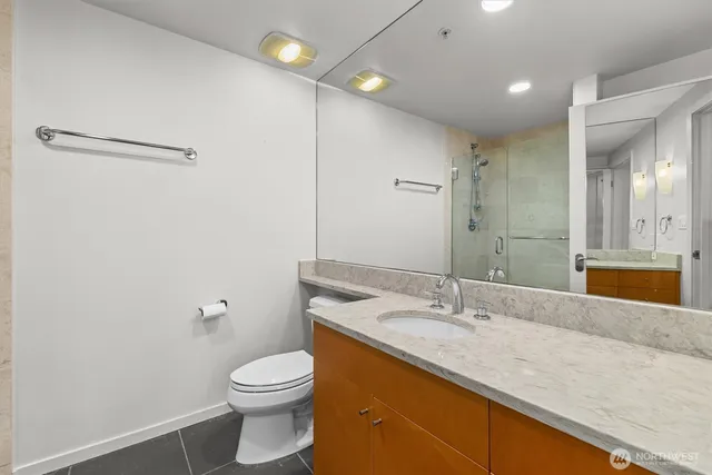 a bathroom with a granite countertop sink a toilet and a mirror