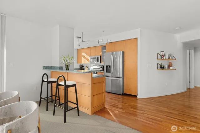 a kitchen with stainless steel appliances wooden floor and chairs