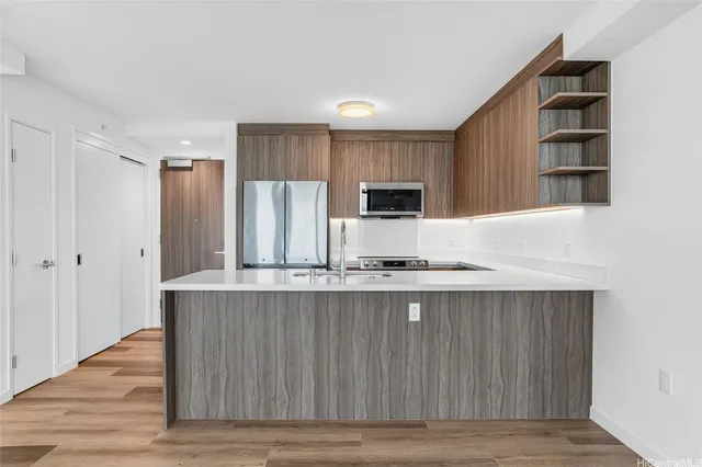 a kitchen with stainless steel appliances a sink a stove a refrigerator cabinets and wooden floor