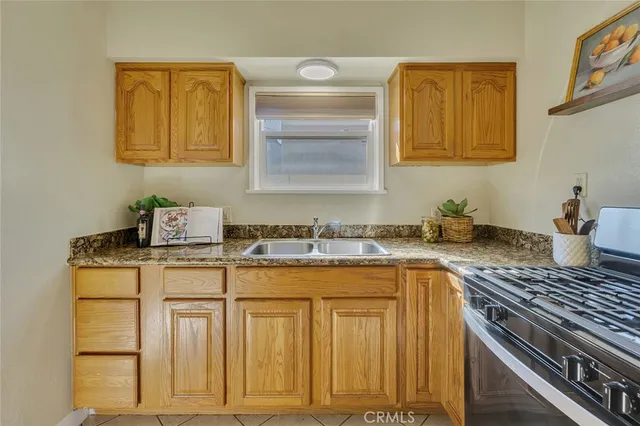 a kitchen with granite countertop a sink stove and cabinets