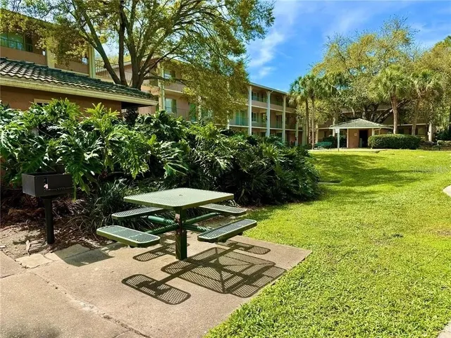 a view of a backyard with table and chairs potted plants and large tree