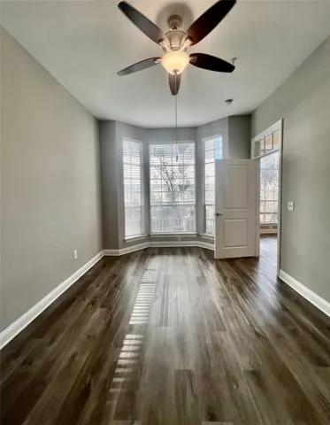 an empty room with wooden floor chandelier fan and windows