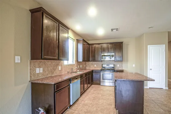 a kitchen with kitchen island granite countertop wooden cabinets and stainless steel appliances