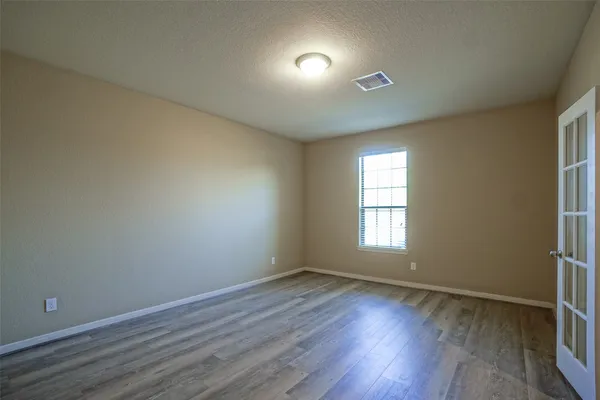 an empty room with wooden floor and windows