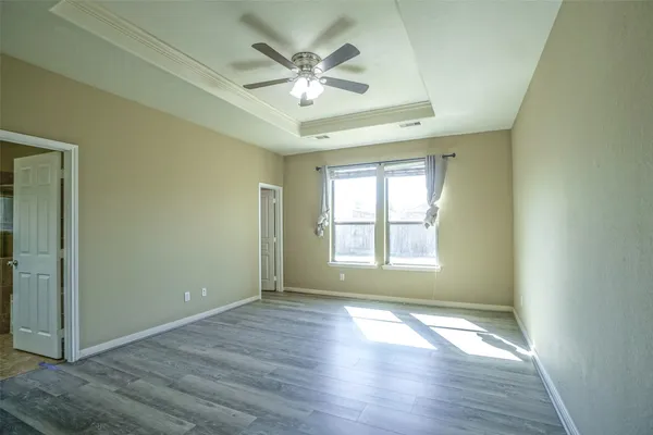 an empty room with wooden floor chandelier fan and windows
