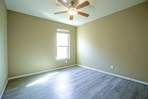 an empty room with a window and a fan