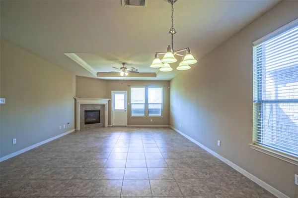 a view of an empty room with a chandelier fan and fireplace