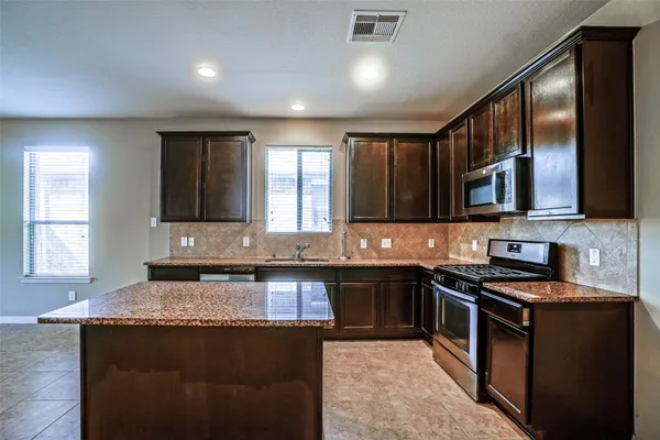 a kitchen with stainless steel appliances granite countertop a stove a sink and a microwave