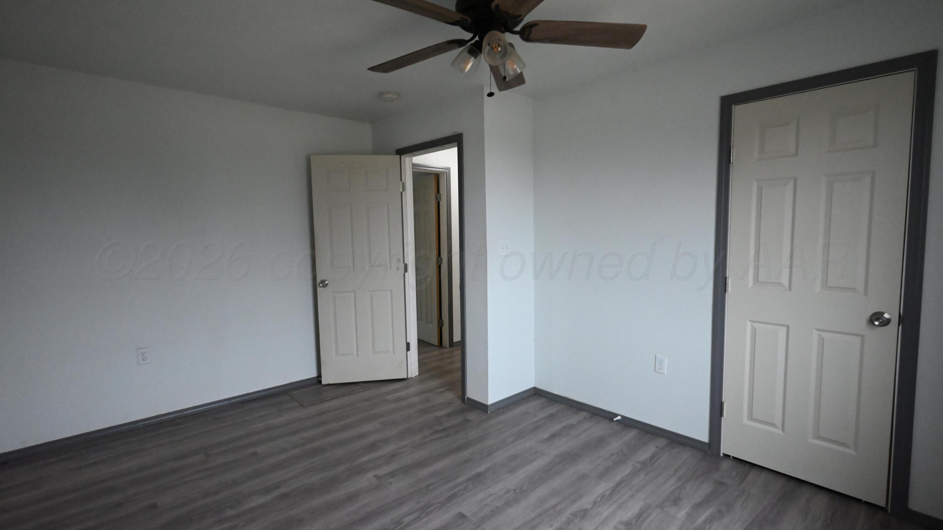 306 Union Street Borger, TX 79007 - Photo 10 of 12 an empty room with wooden floor a ceiling fan and windows