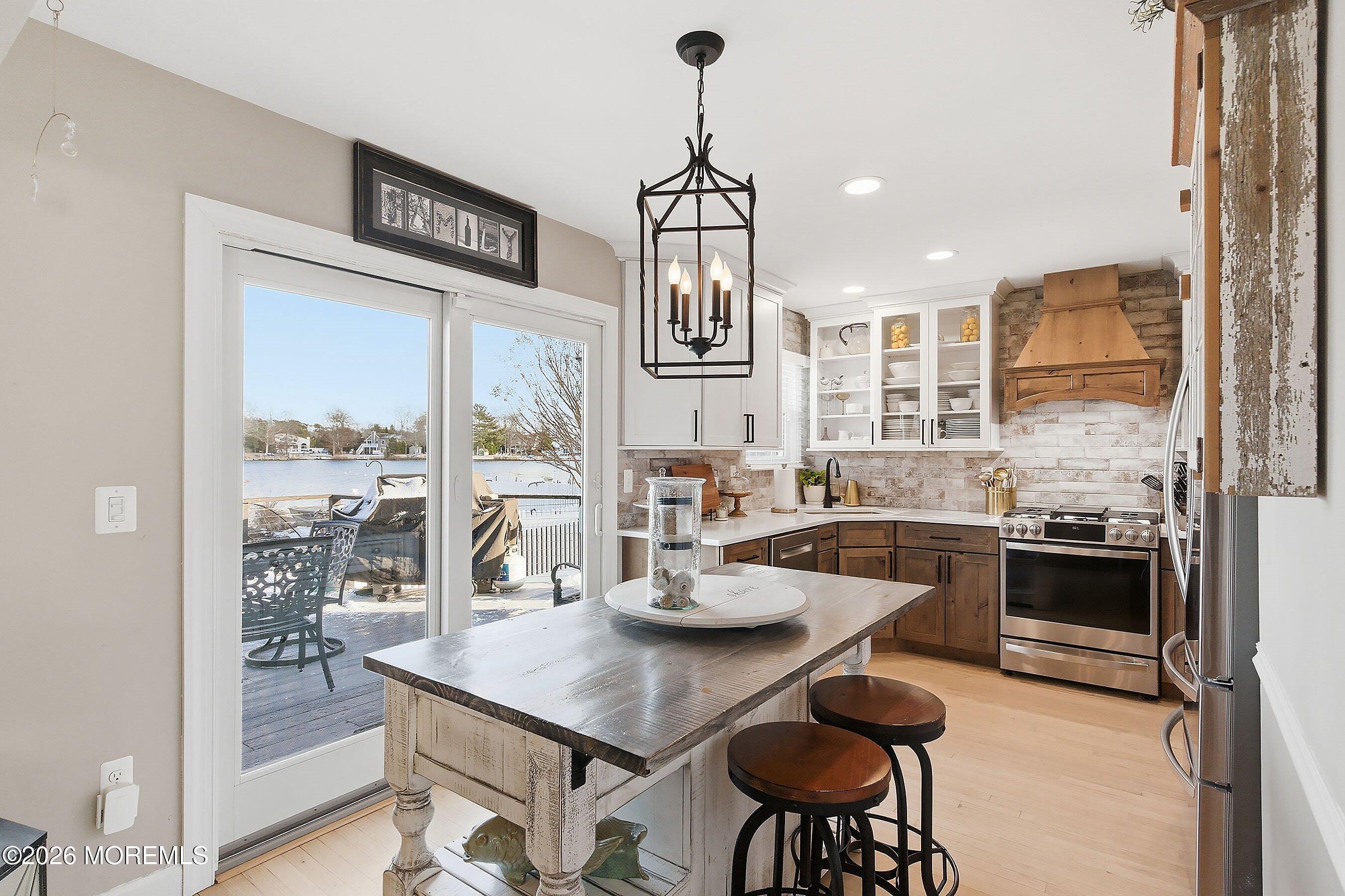 261 Timberlake Drive Manahawkin, NJ 08050 - Photo 17 of 64 a kitchen with stainless steel appliances granite countertop a stove a refrigerator a kitchen island a dining table and chairs with wooden floor