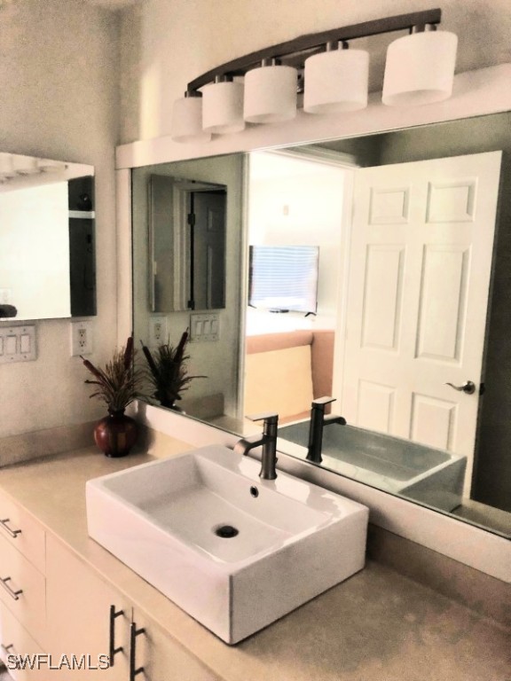 4440 Botanical Pl Circle, Unit 102 Naples, FL 34112 - Photo 9 of 21 a bathroom with a sink and a mirror