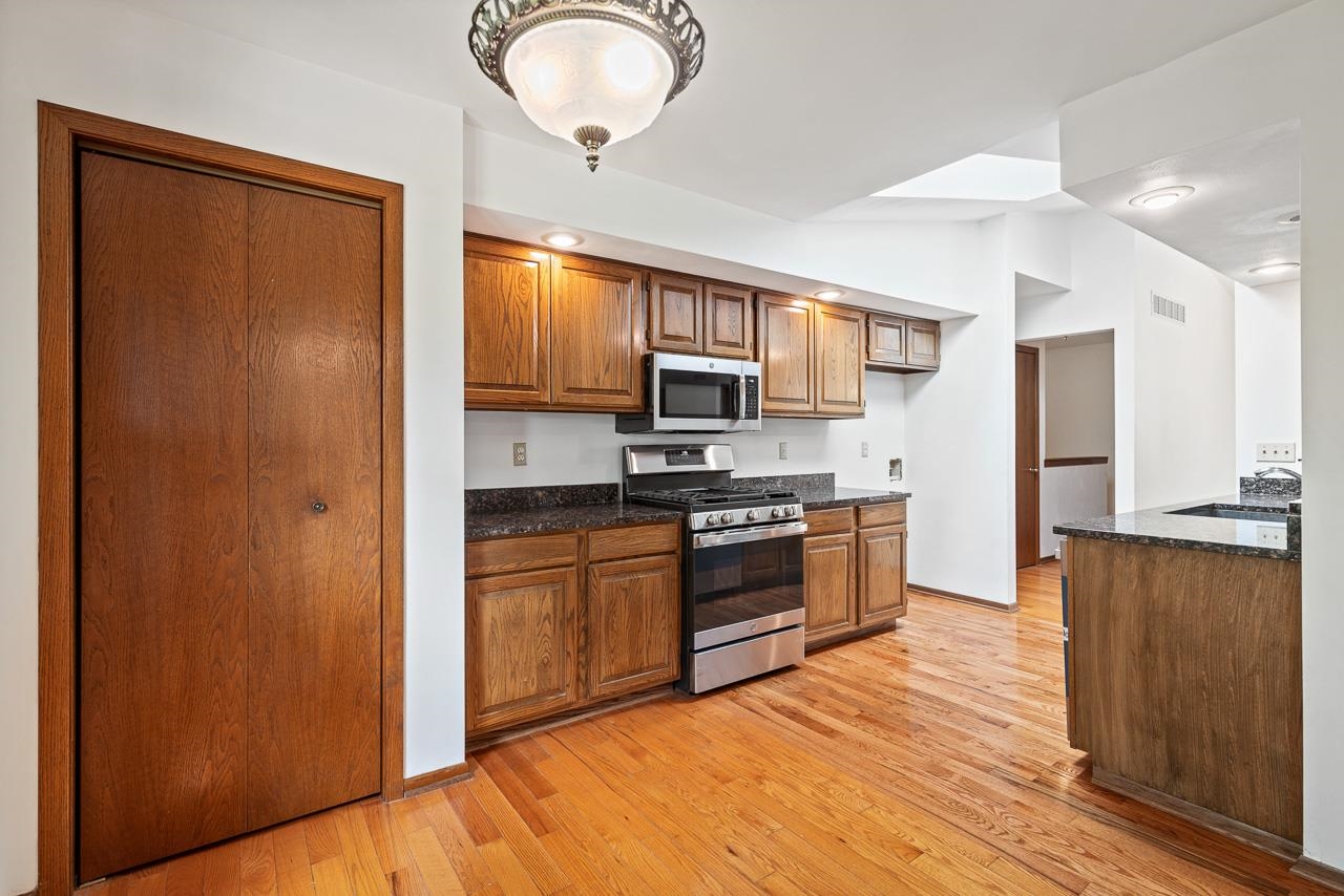 3442 North Trainer Road Rockford, IL 61114 - Photo 10 of 35 a kitchen with stainless steel appliances granite countertop a refrigerator a stove top oven a sink and dishwasher with wooden floor