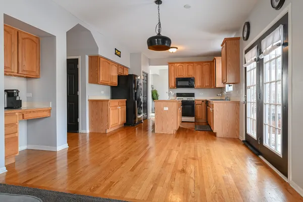 a open kitchen with stainless steel appliances granite countertop a stove top oven a refrigerator a sink with island and chairs