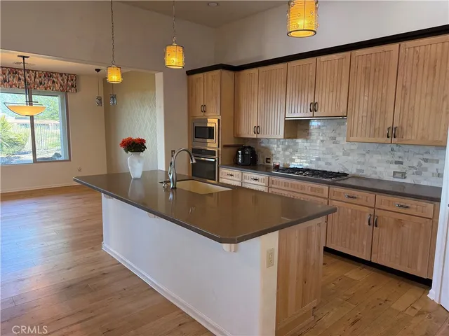 a kitchen with kitchen island granite countertop a sink a stove and a cabinets