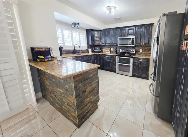 a kitchen with stainless steel appliances granite countertop a stove refrigerator and a microwave