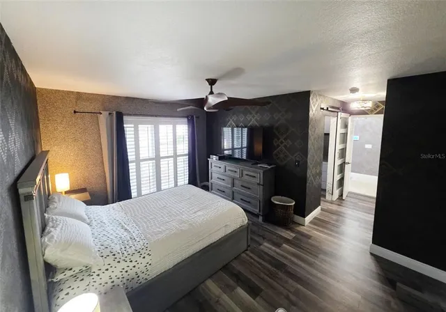 a spacious bedroom with a bed a mirror on dresser and a window