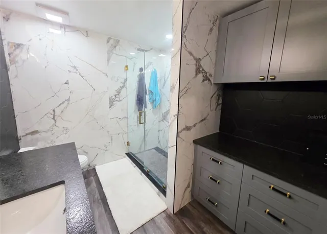 a bathroom with a granite countertop sink a vanity and shower
