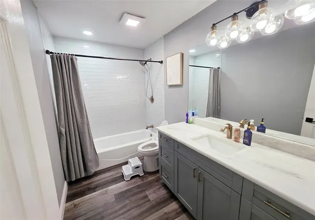 a bathroom with a sink a toilet a mirror a bathtub and shower