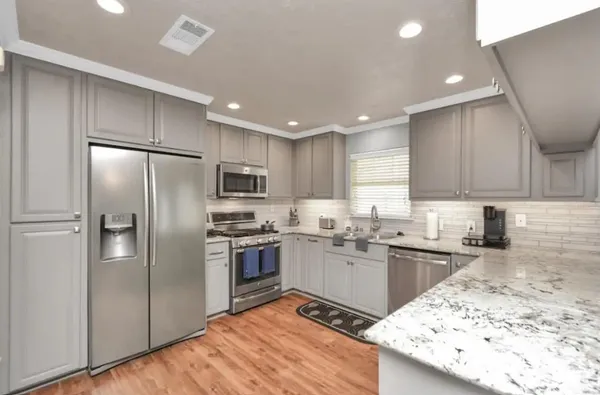 a kitchen with granite countertop stainless steel appliances cabinets a sink and a counter top space