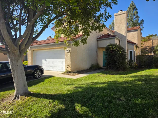a view of a house with backyard and a tree