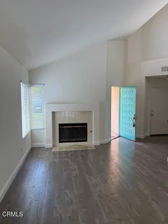an empty room with wooden floor fireplace and windows