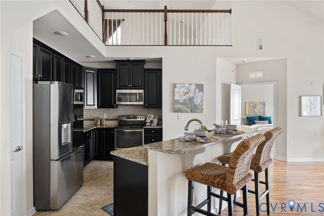 1201 Westwood Village Lane, Unit 402 Midlothian, VA 23114 - Photo 3 of 27 a kitchen with stainless steel appliances granite countertop a refrigerator a stove a sink a dining table and chairs