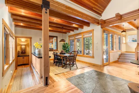 a dining room with wooden floor a chandelier a glass table and chairs