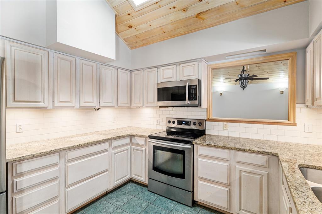 2023 Southwest 76 Terrace Gainesville, FL 32607 - Photo 37 of 95 a kitchen with granite countertop white cabinets white stainless steel appliances and sink
