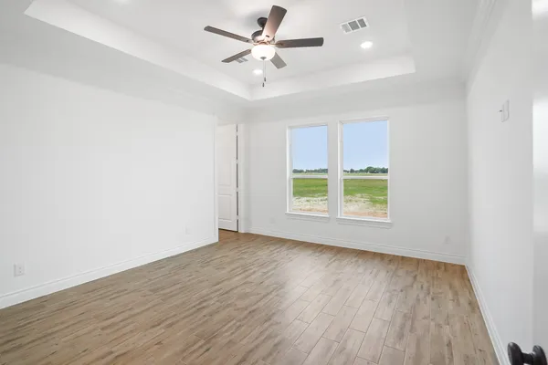 an empty room with wooden floor and windows