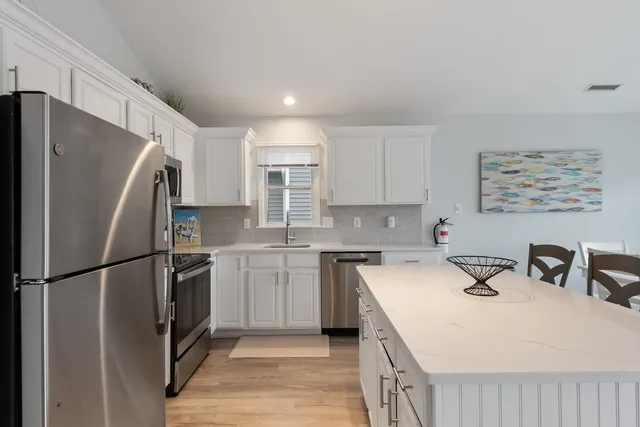a kitchen with a sink a refrigerator and white cabinets