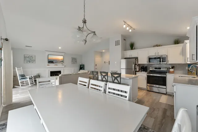 a living room with stainless steel appliances furniture a rug and a kitchen view
