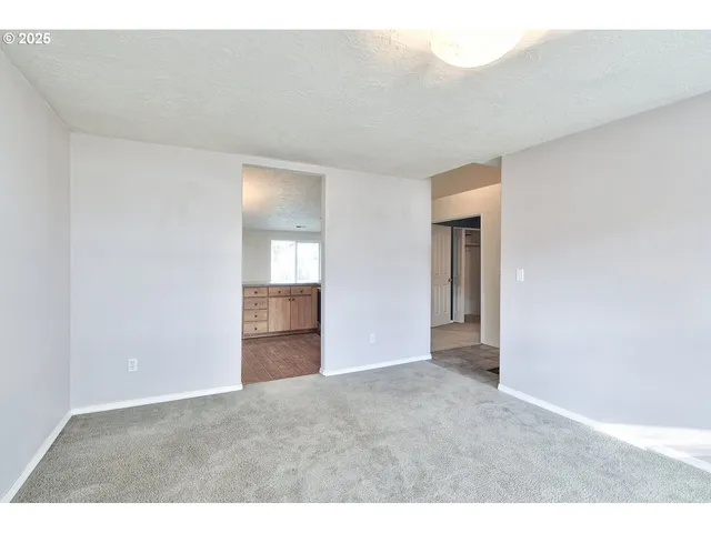 a view of an empty room with closet and bathroom