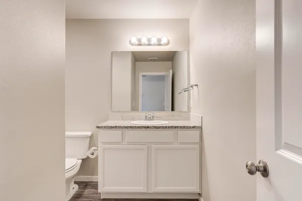 a bathroom with a granite countertop toilet sink and mirror