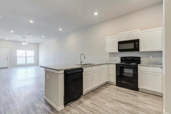 a kitchen with granite countertop a stove and a wooden floor