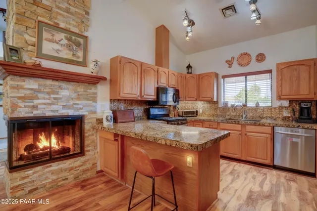 a kitchen with stainless steel appliances granite countertop a sink a stove and a wooden floors