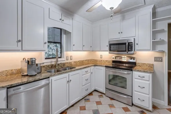 a kitchen with granite countertop a sink stove and microwave