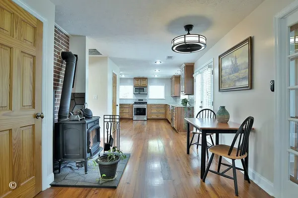 a kitchen with stainless steel appliances granite countertop wooden cabinets a refrigerator a sink a stove and a wooden floors