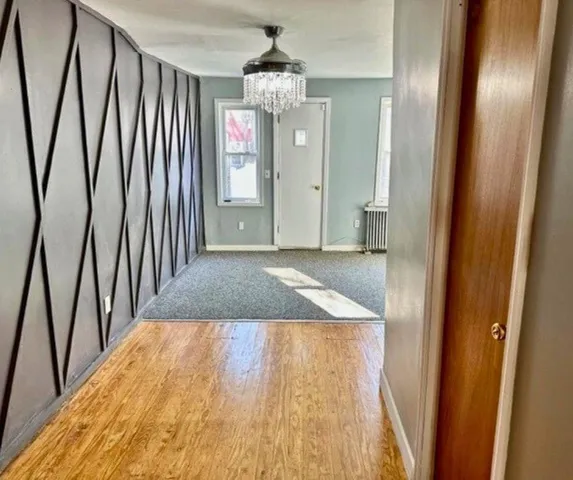 a view of a hallway with wooden floor and chandelier