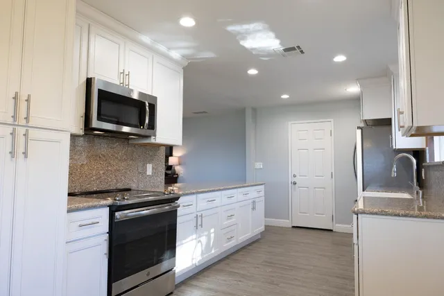 a kitchen with stainless steel appliances granite countertop a stove a sink and a microwave