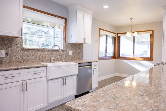 a kitchen with white cabinets and a large window
