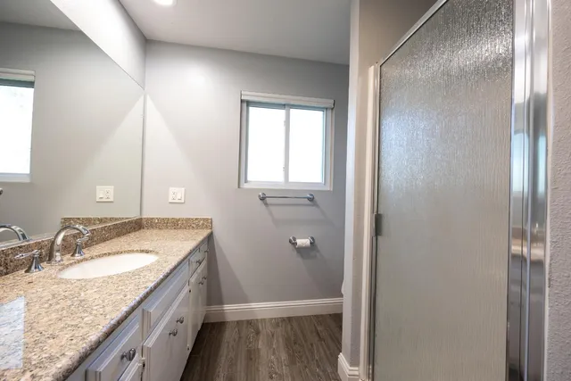 a bathroom with a granite countertop sink a mirror and a shower